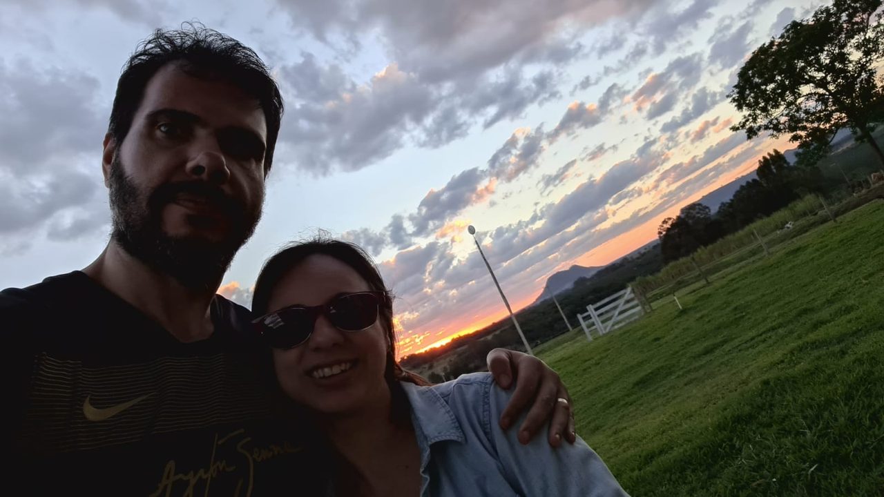 Casal em selfie ao pôr do sol com o morro ao fundo